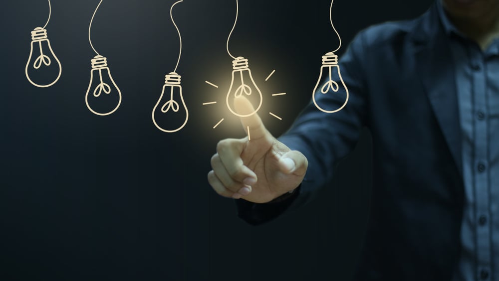 man in suit touching lit up light bulb